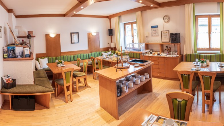 A cozy breakfast room with wooden furniture, laid tables and a buffet.