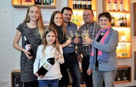 Family with wine bottles and glasses in a wine cellar.