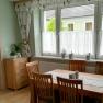 Dining room with wooden table, chairs and plants on the windowsill.