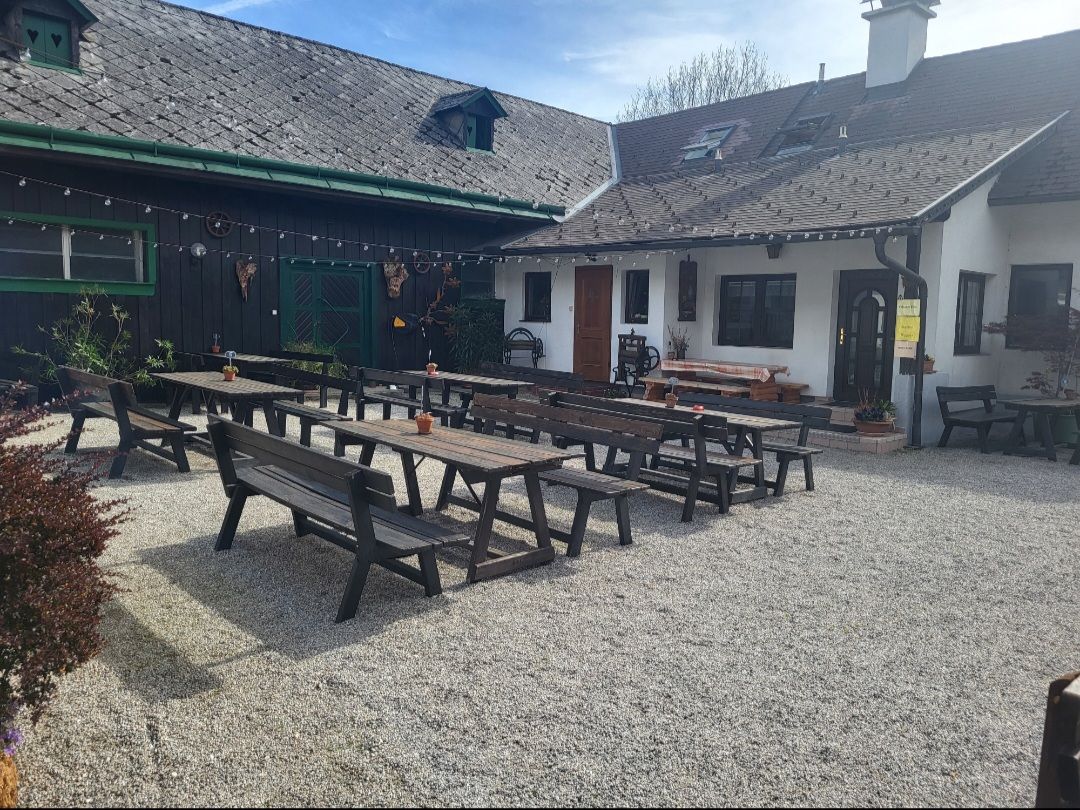 A guest garden with wooden benches and tables on gravel in front of a traditional building.