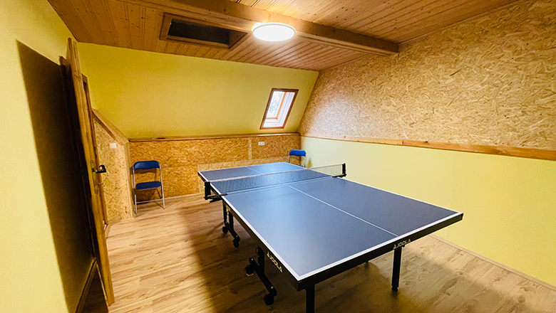 A playroom with table tennis table, yellow walls and wooden ceiling.