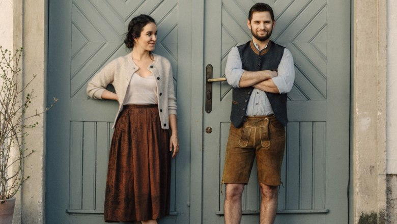 Two people in traditional dress in front of a blue wooden door.