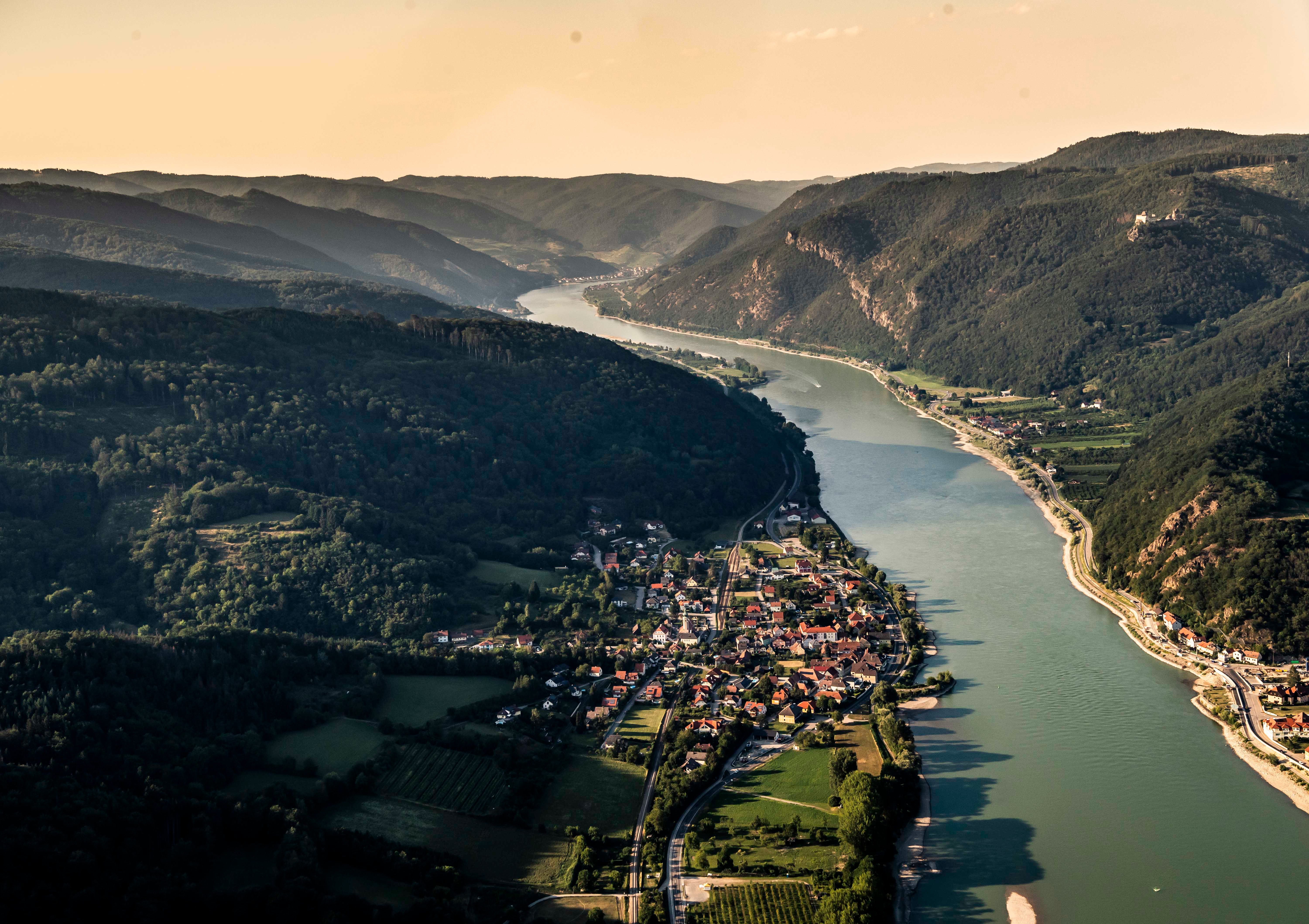Aerial view of Aggsbach Markt an der Donau, surrounded by hills and forests.