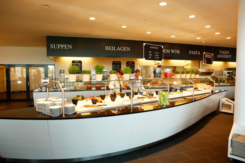 Interior view of a modern restaurant with buffet and food offerings on the wall.