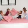 Family having pillow fight on a bed with red and white checkered bedding.