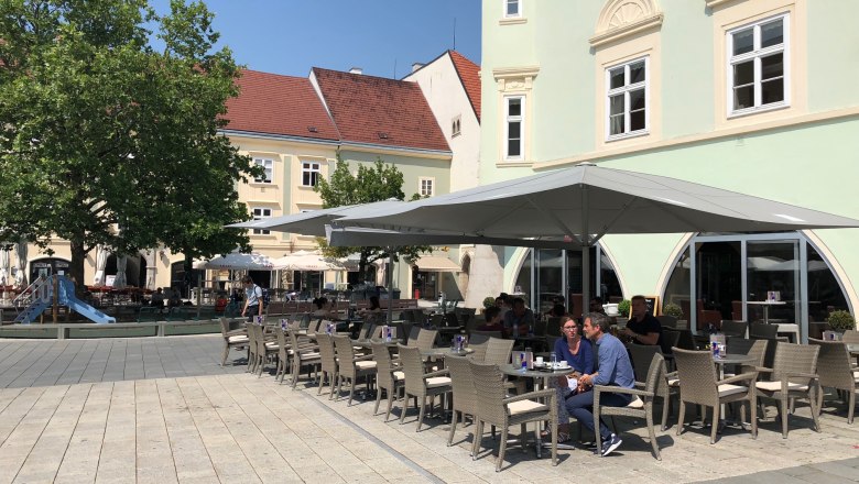 A pavement garden in front of the Eterno with parasols and seating on a paved square.