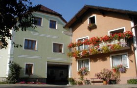 Two farm buildings with colorful flowers on the balconies.