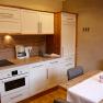 Modern kitchen with white cupboards, wooden worktop, dining table and chairs.