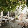Cozy courtyard with tables, chairs and green arbor.