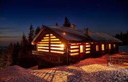 In der winterlichen Stille erstrahlt die Anna Alm in warmem Licht, während der Schnee sanft die Umgebung bedeckt. Die gemütliche Hütte lädt dazu ein, nach einem aufregenden Skitag am Hennesteck zu verweilen und die atemberaubende Aussicht auf die verschneiten Berge zu genießen.
