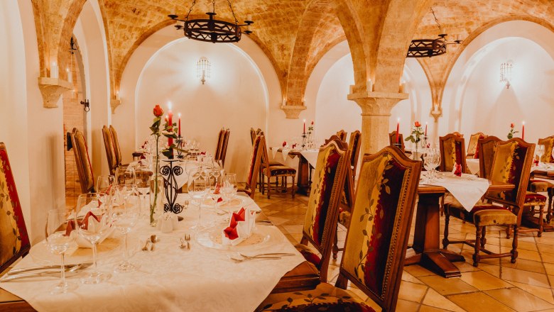 Elegant vaulted cellar with laid tables and candlelight.