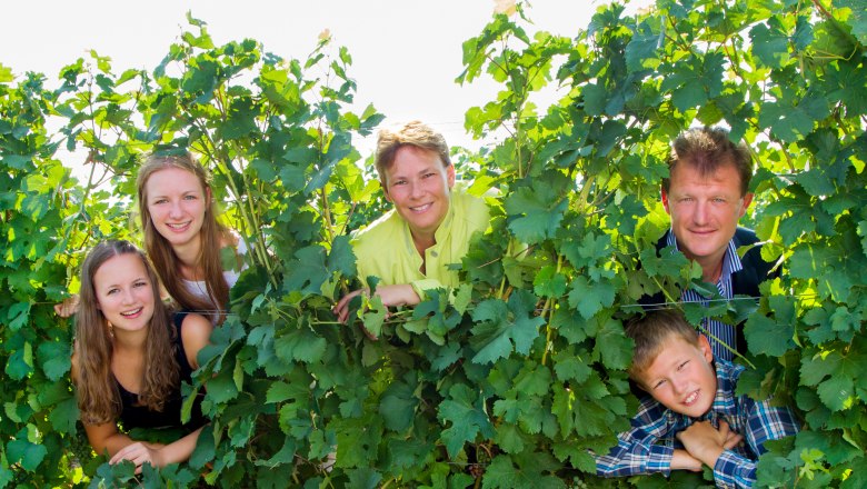 A family looks through vines with a smile.