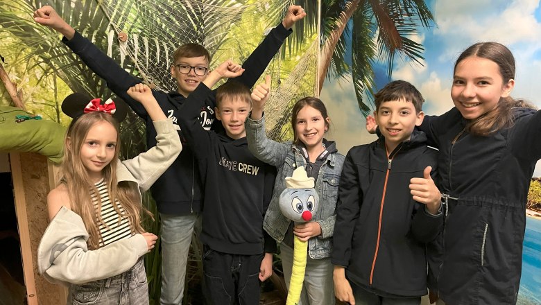 6 children in front of a jungle picture are happy that the puzzle has been solved