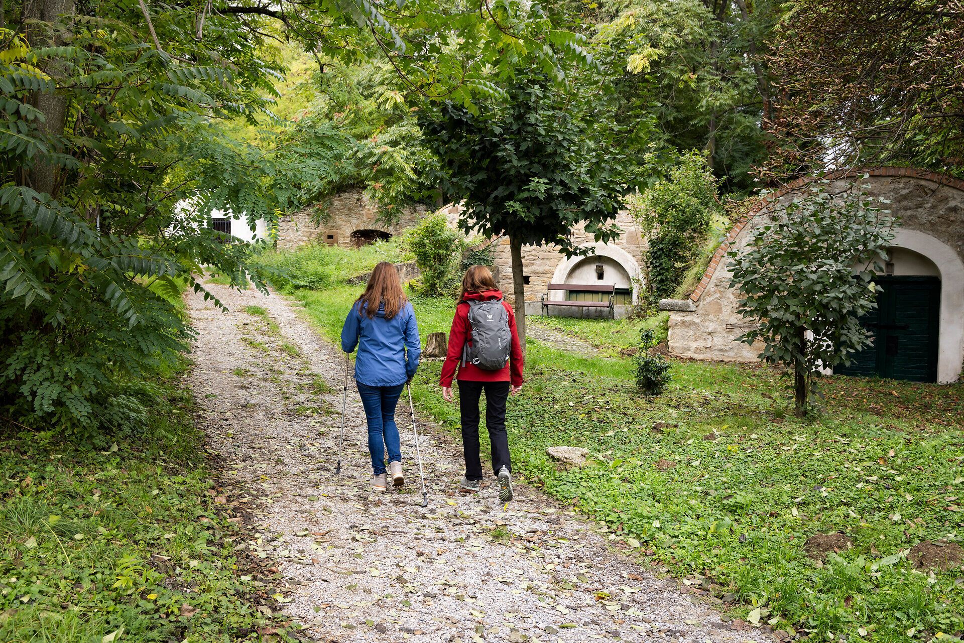 Two women on a footpath through a cellar district. 