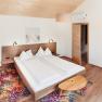 Modern bedroom with double bed, wooden furniture and colorful carpet.