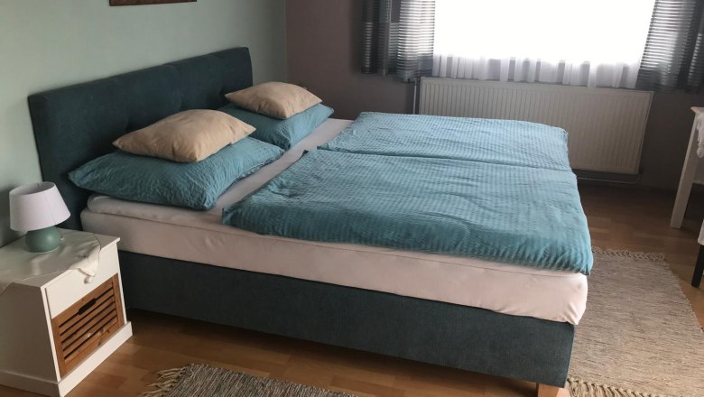 Bedroom with double bed, blue bed linen and bedside table with lamp.