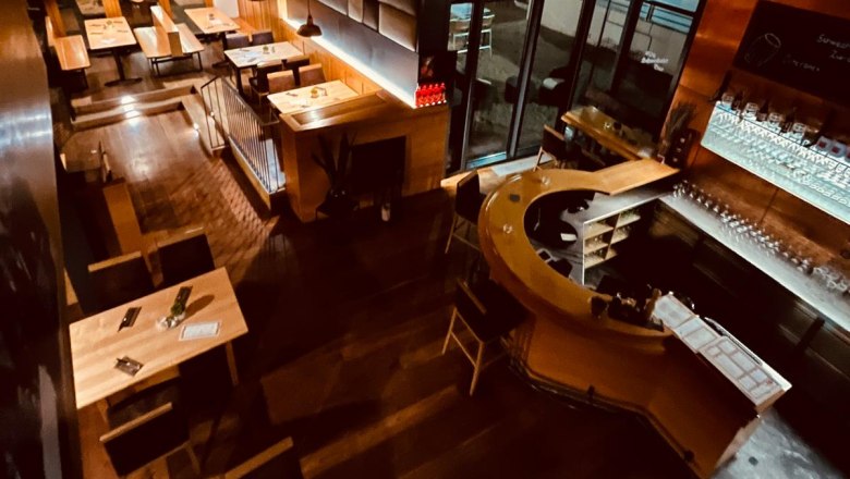Interior view of Brauhaus Schwechat at night with wooden tables and a bar.