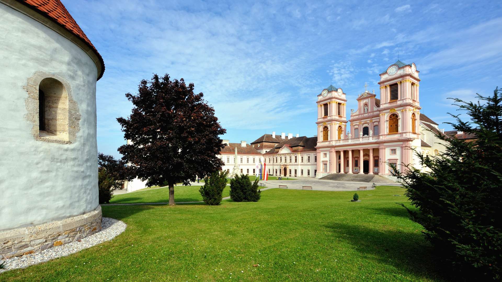 Inner courtyard of Göttweig Abbey with green meadow, trees and baroque architecture in the background.