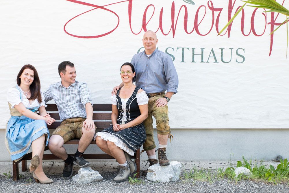 Four people in traditional dress in front of an inn sign.