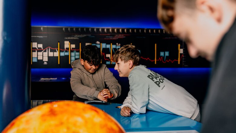 Two boys interact at a blue table in a science center.