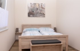 Bedroom with double bed, wooden furniture and abstract artwork on the wall.
