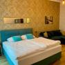 Elegant hotel room with double bed, blue couch and golden wallpaper.