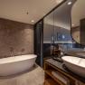 Modern hotel room with free-standing bathtub and washbasin.