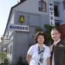 A man and a woman are standing in front of a building labeled 'Hotel Burger'.
