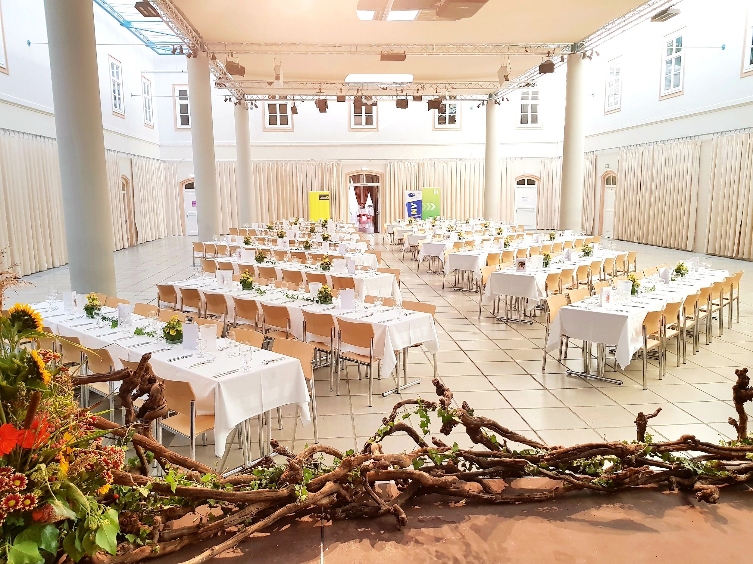 A festively decorated hall with laid tables and floral decorations in the Atrium Tulln.