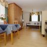 Small apartment with wooden furniture, dining table, chairs, bed and kitchenette.