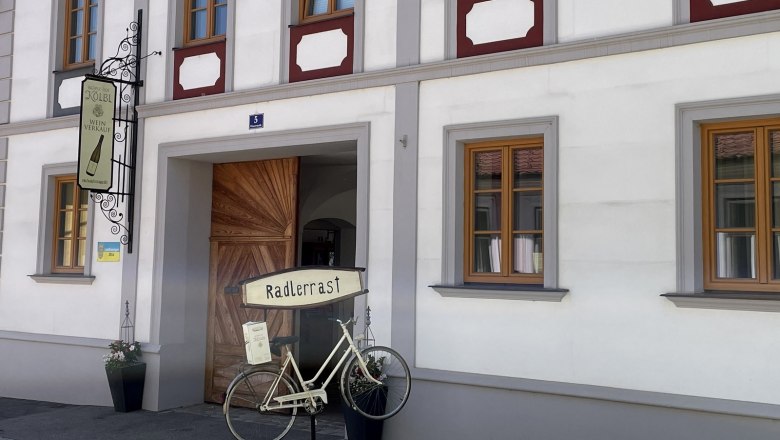 Facade of a building with sign 'Radlerrast' and a decorative bicycle.