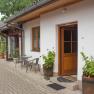 Exterior view of a garden room with wooden door, windows and plants in pots.