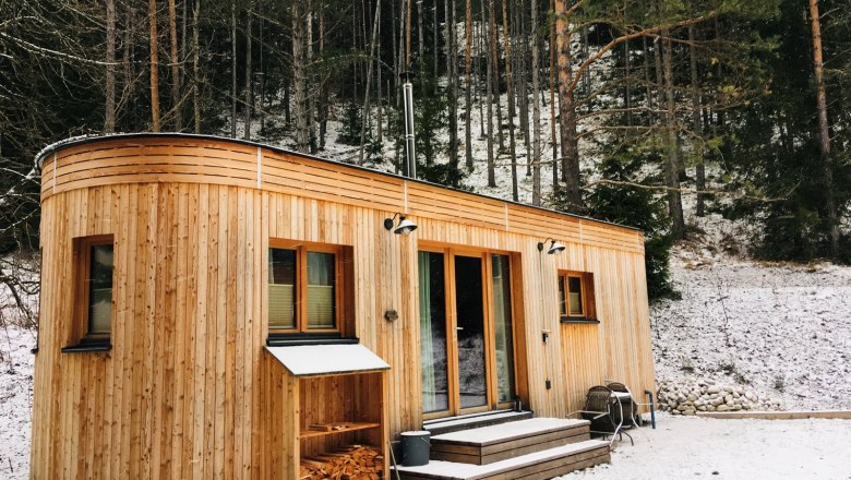 A wooden caravan stands in the snowy forest.