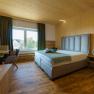Modern hotel room with double bed, wooden walls and large window.