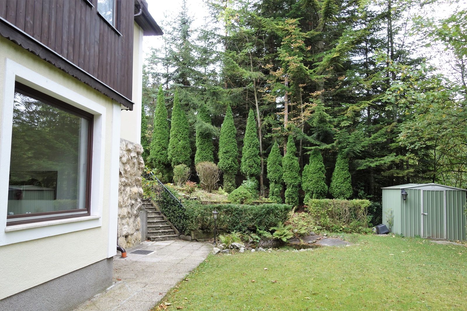 Garden with lawn, trees and a shed.
