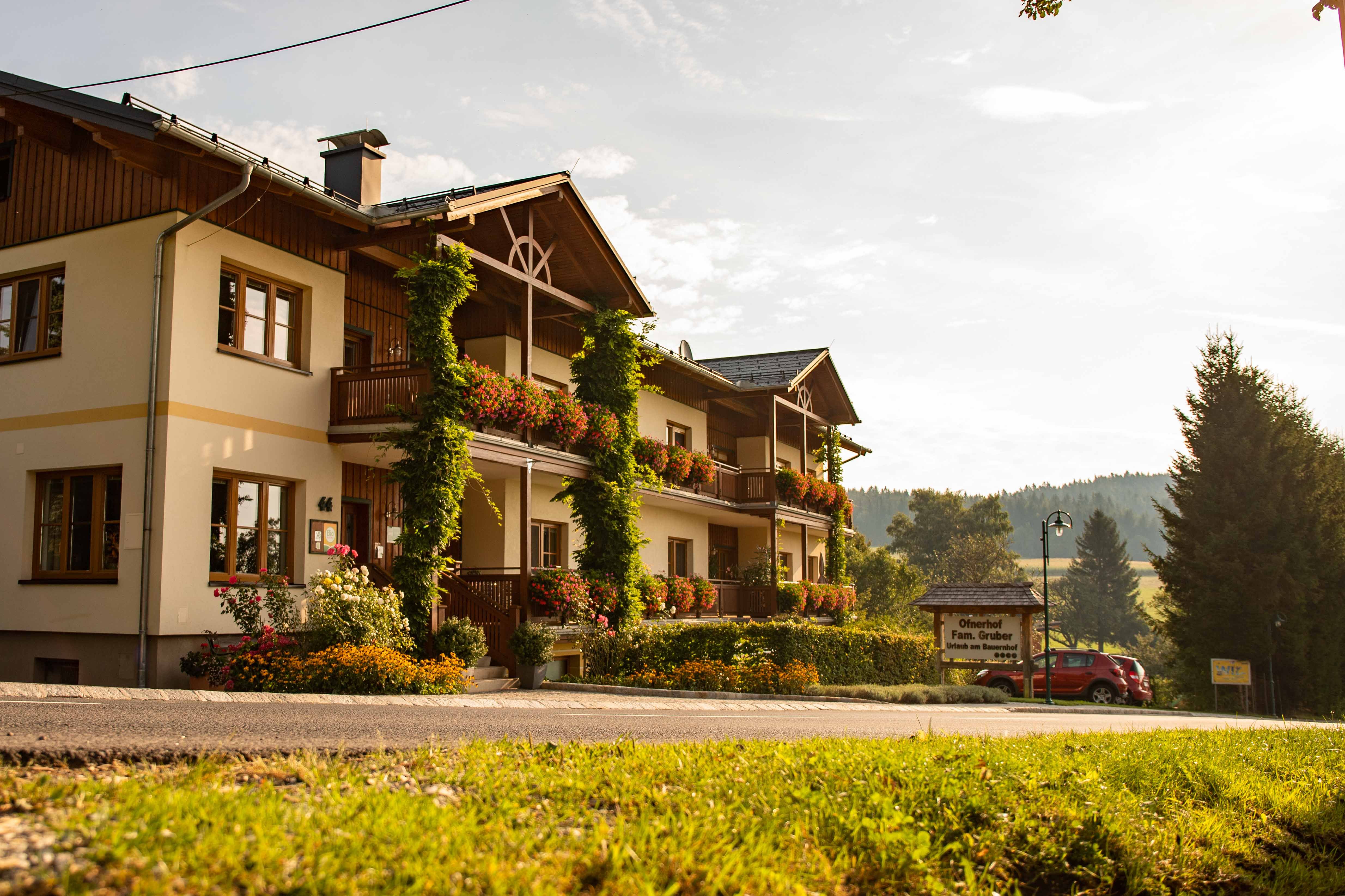 A traditional inn with balconies decorated with flowers in a rural setting at sunset.