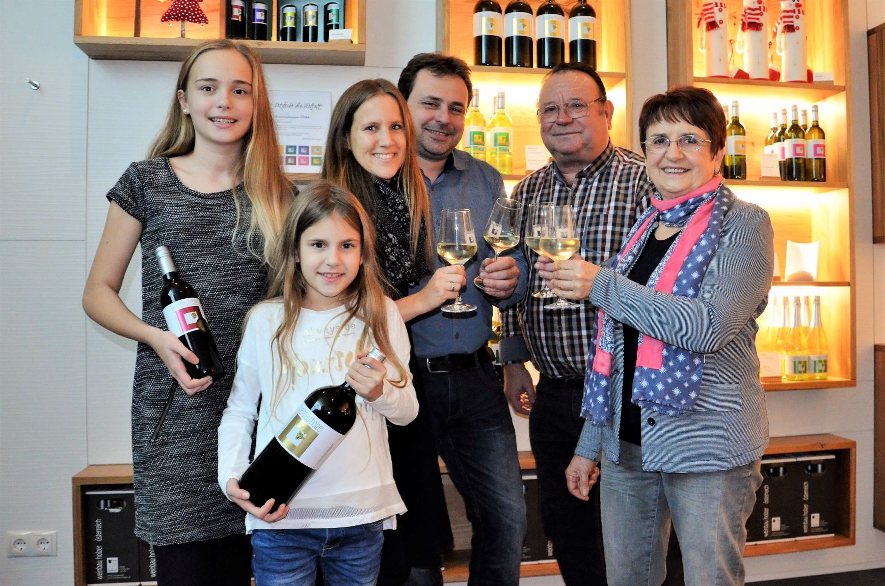 Family with wine bottles and glasses in a wine cellar.