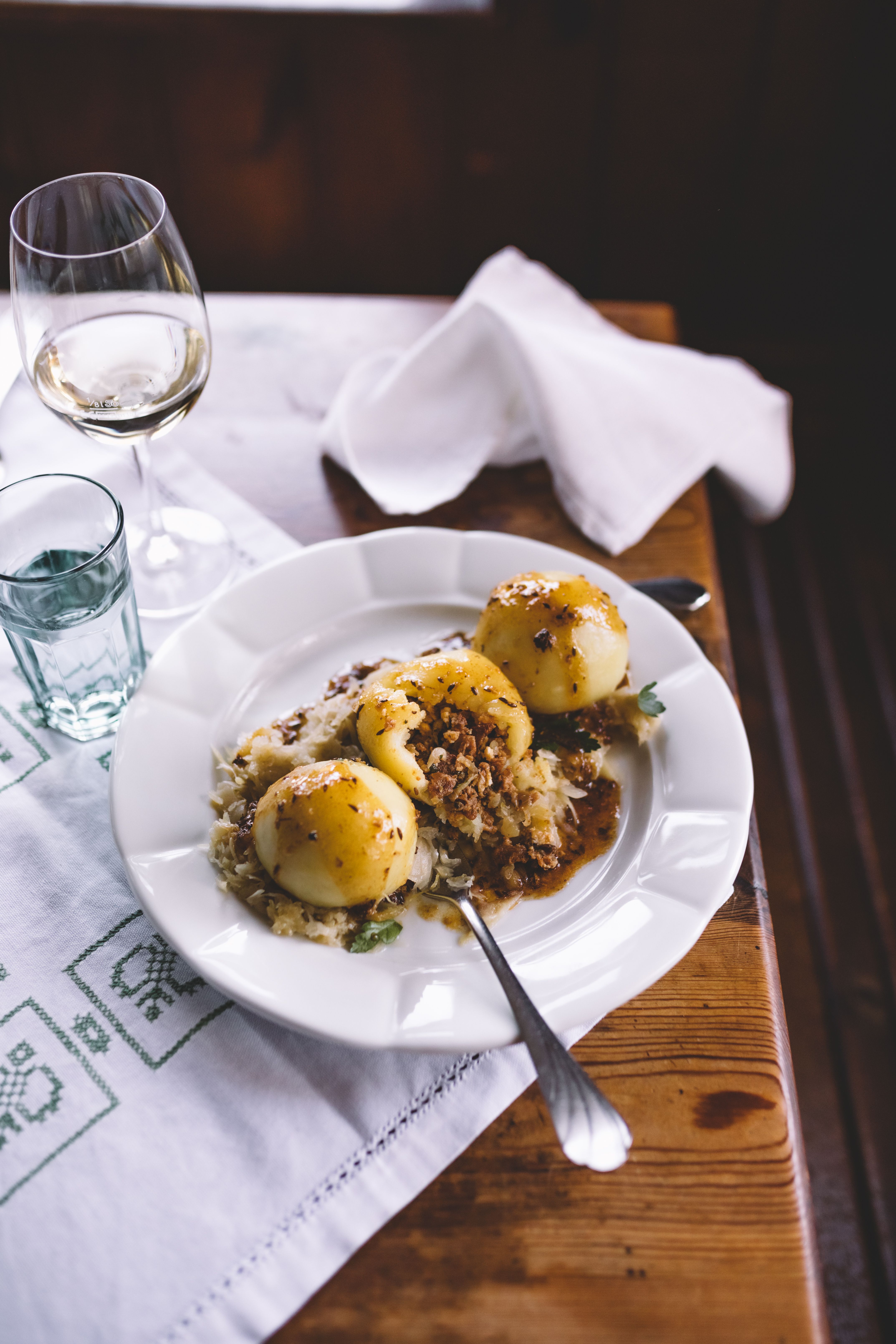 A dessert plate with a nougat tartlet, elderberry ice cream, berries and a spoon on a wooden table.