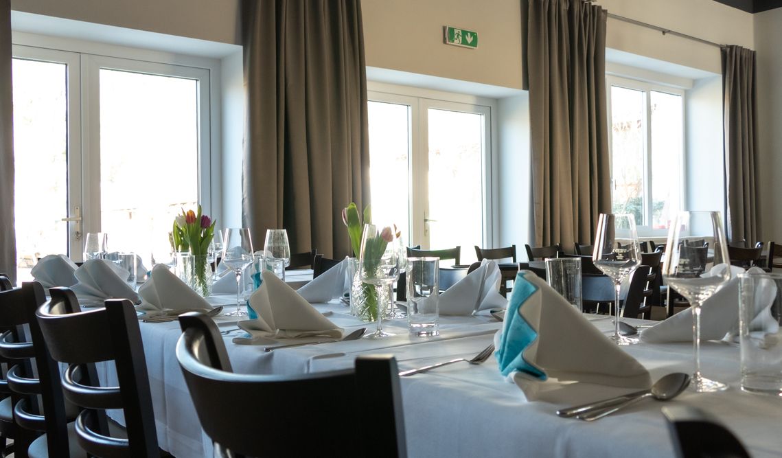 Elegant restaurant with laid tables, white tablecloths and folded napkins.