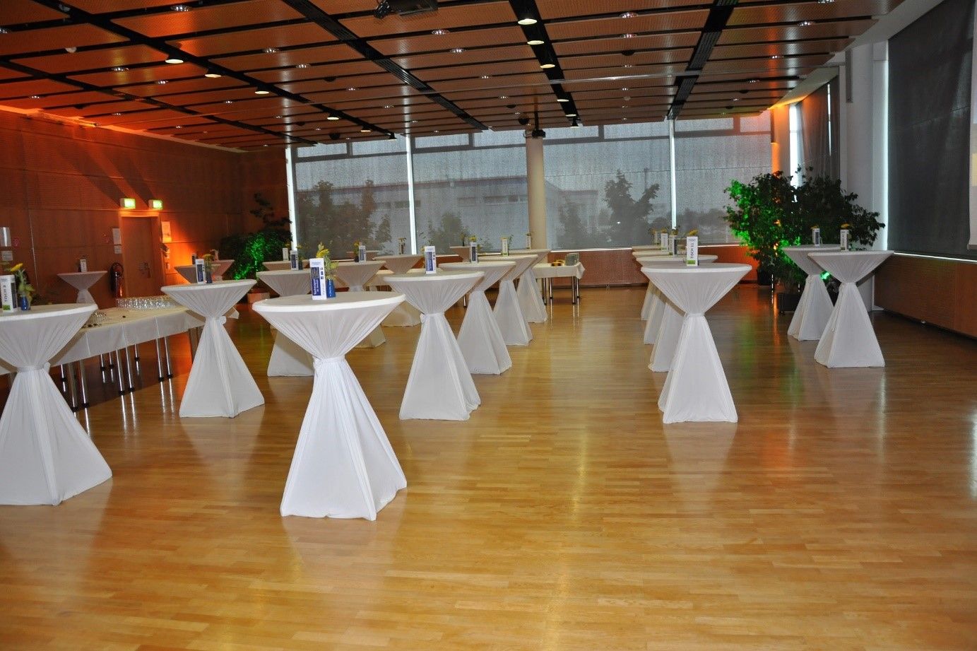 An empty function room with bar tables covered with white tablecloths.