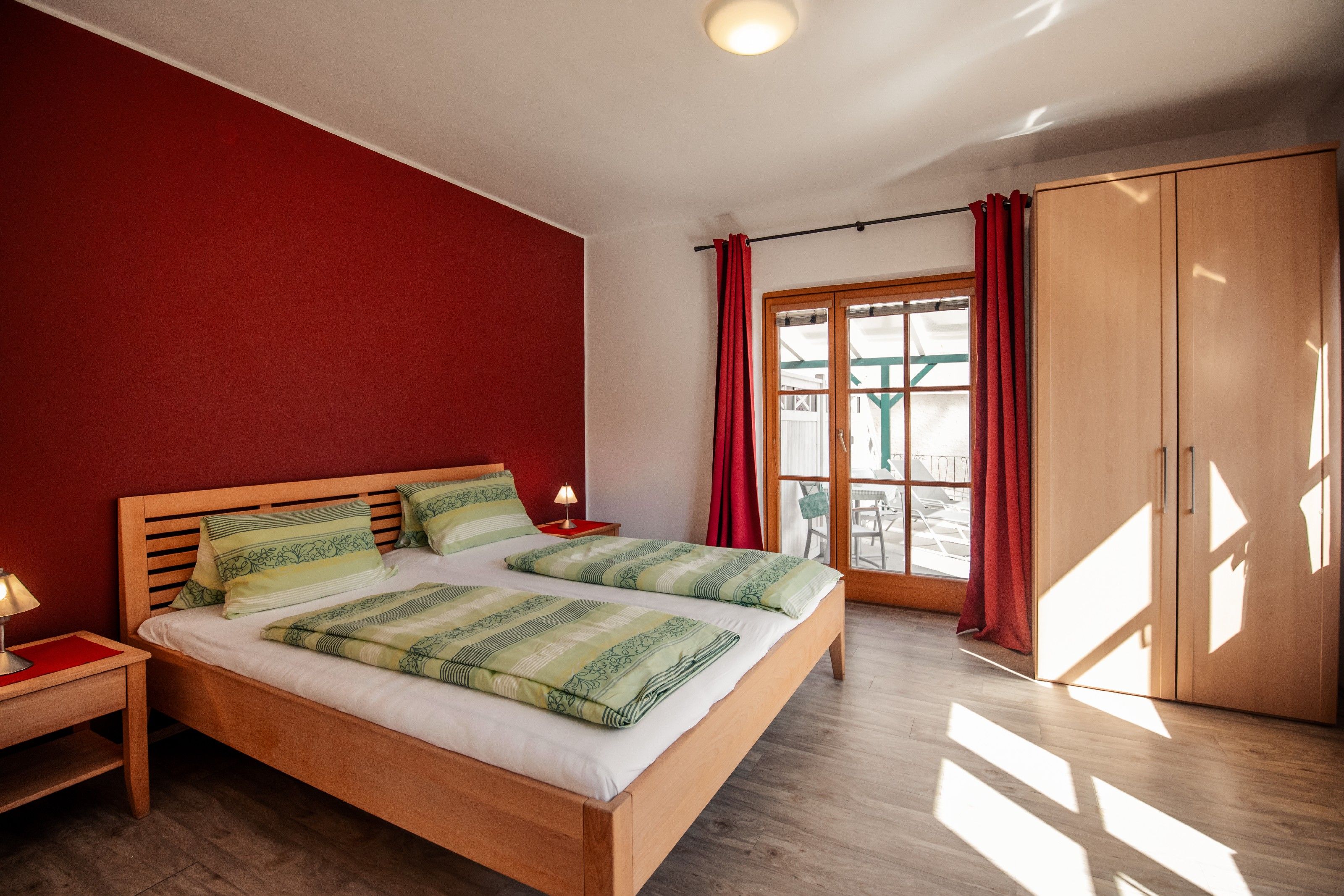 Bedroom with double bed, red wall and wooden furniture.