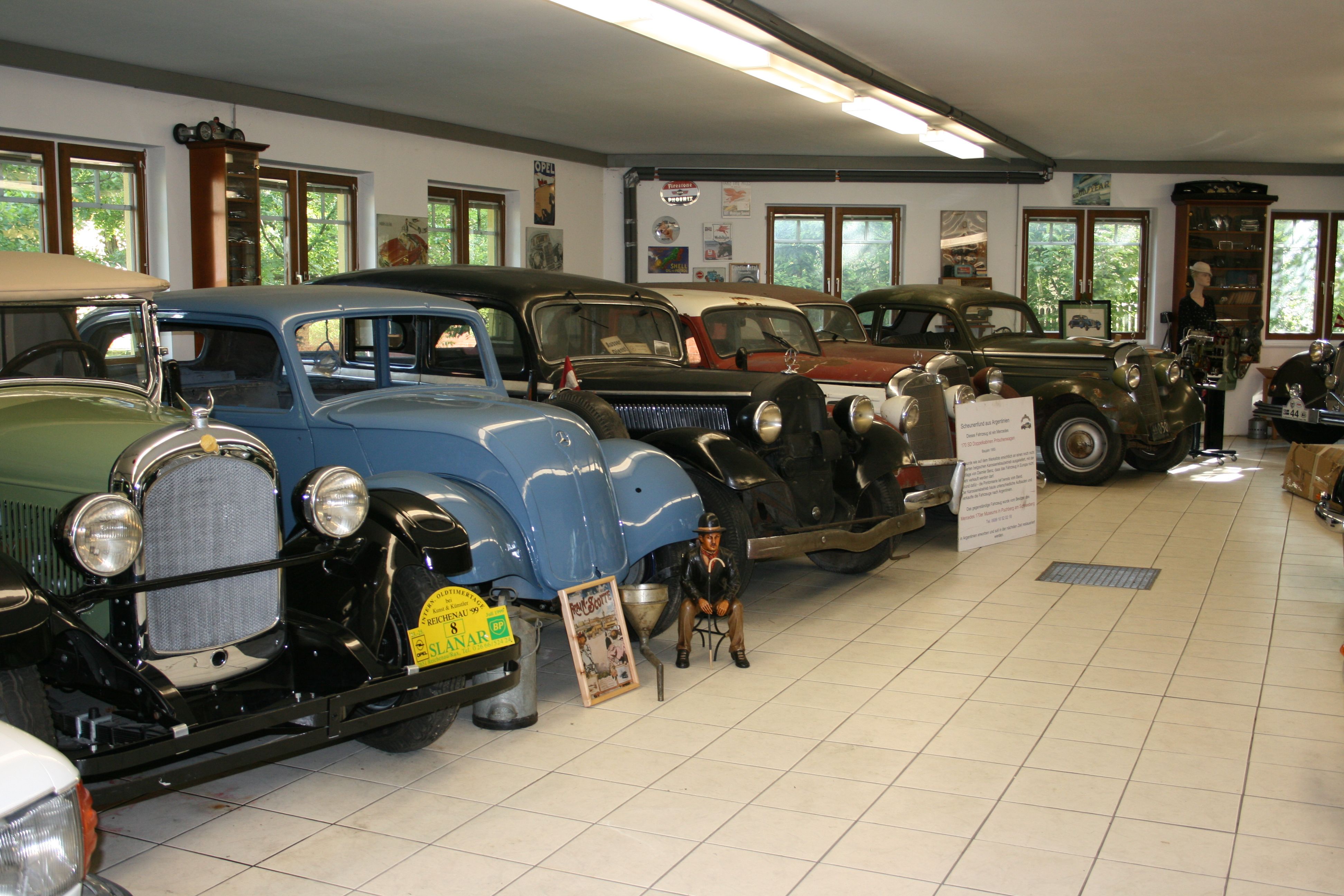 Interior view of a classic car museum with several classic cars in a row.