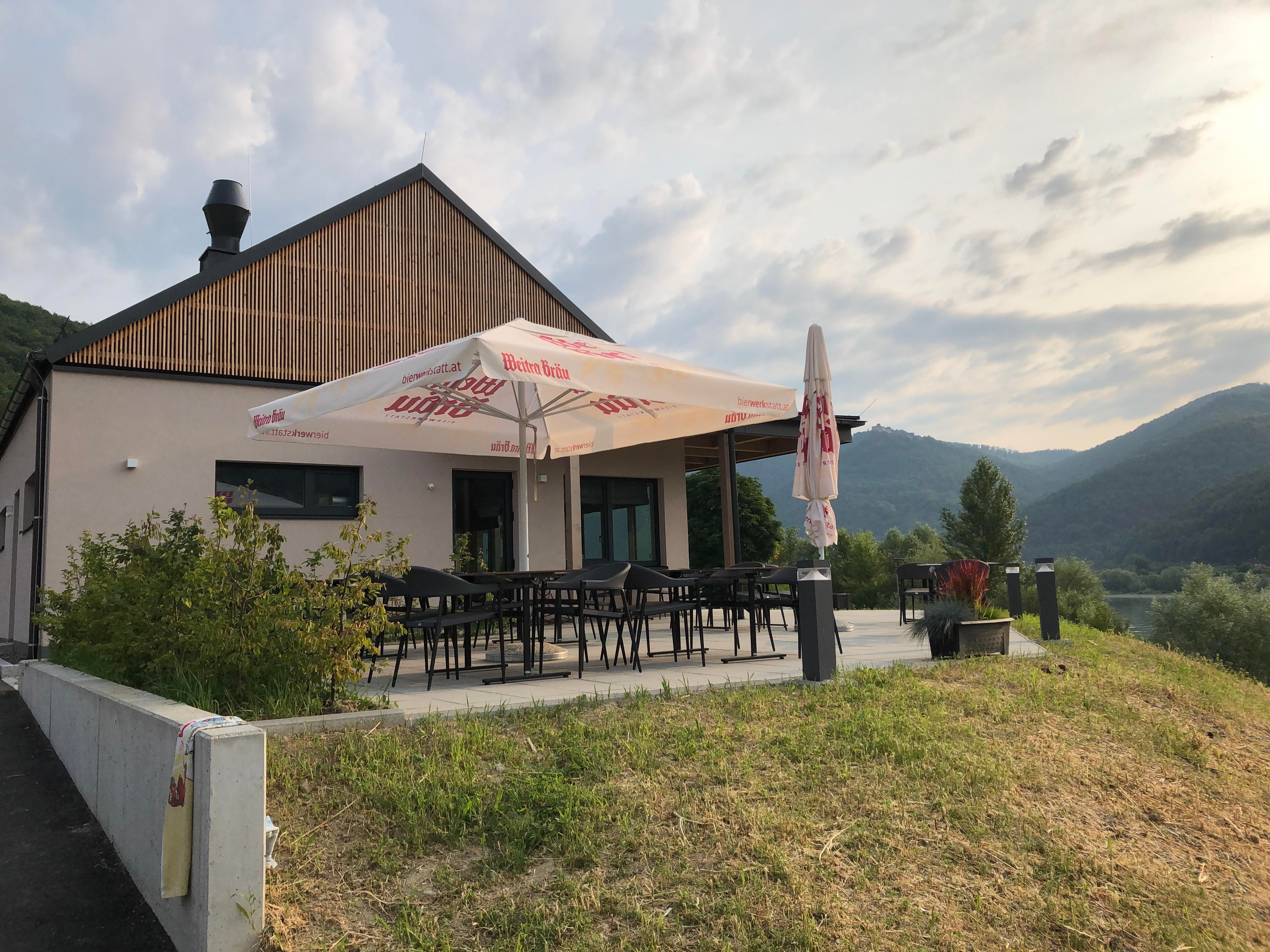 Modern terrace with parasol, surrounded by green landscape and hills.
