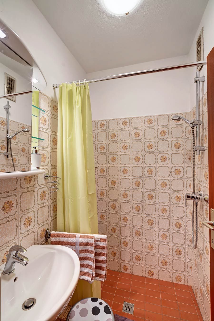 Small bathroom with yellow shower curtain, washbasin and patterned tiles.