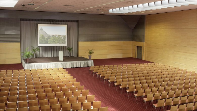 Large conference hall with stage and rows of chairs.
