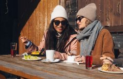 In der winterlichen Idylle genießen Freunde eine entspannte Zeit bei köstlichen Speisen und warmen Getränken. Die schneebedeckten Berge im Hintergrund schaffen eine malerische Kulisse, die zum Verweilen einlädt. Hier wird die Gemütlichkeit der Wiener Alpen in vollen Zügen erlebt.