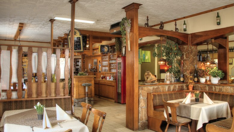 Interior view of a rustic inn with wooden furniture and decorative plants.