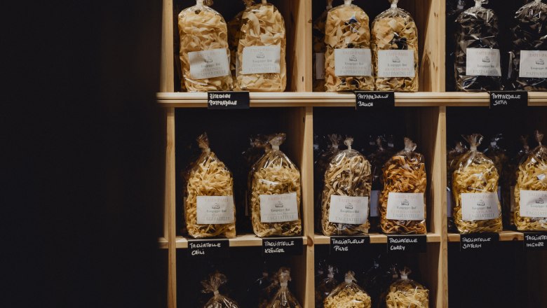 Shelf with different types of packaged pasta in bags.