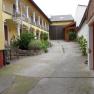 An inner courtyard with a yellow building, plants and a metal staircase.