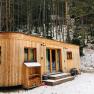 A wooden caravan stands in the snowy forest.